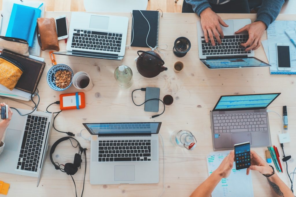 Several individuals seated at a table with laptops, engaged in a discussion about technology expense management solutions.